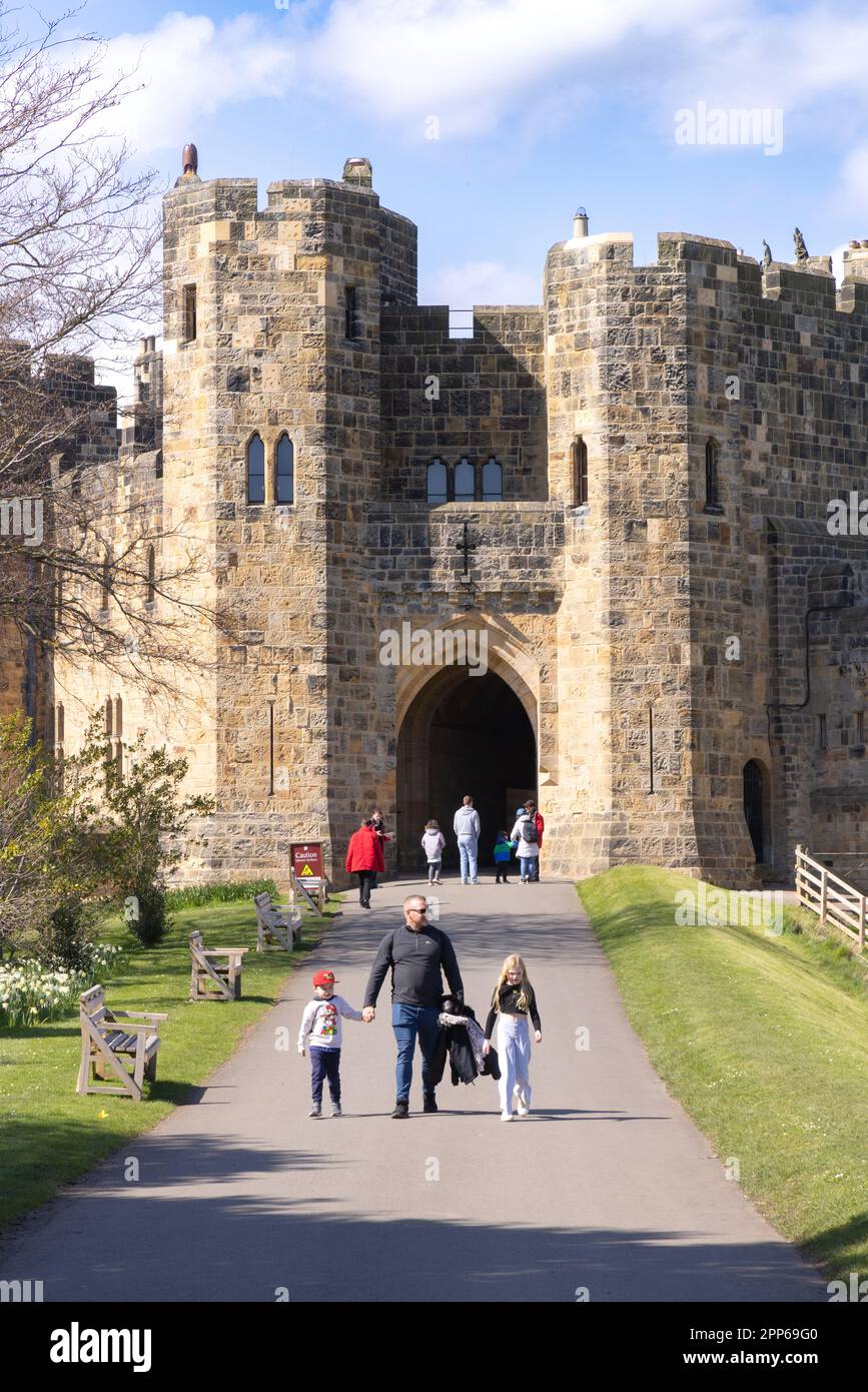 Eingang zur Burg Alnwick; eine mittelalterliche Burg aus dem 12. Jahrhundert. Familie in den Schlossgärten an einem sonnigen Frühlingstag; Alnwick Northumberland UK Stockfoto