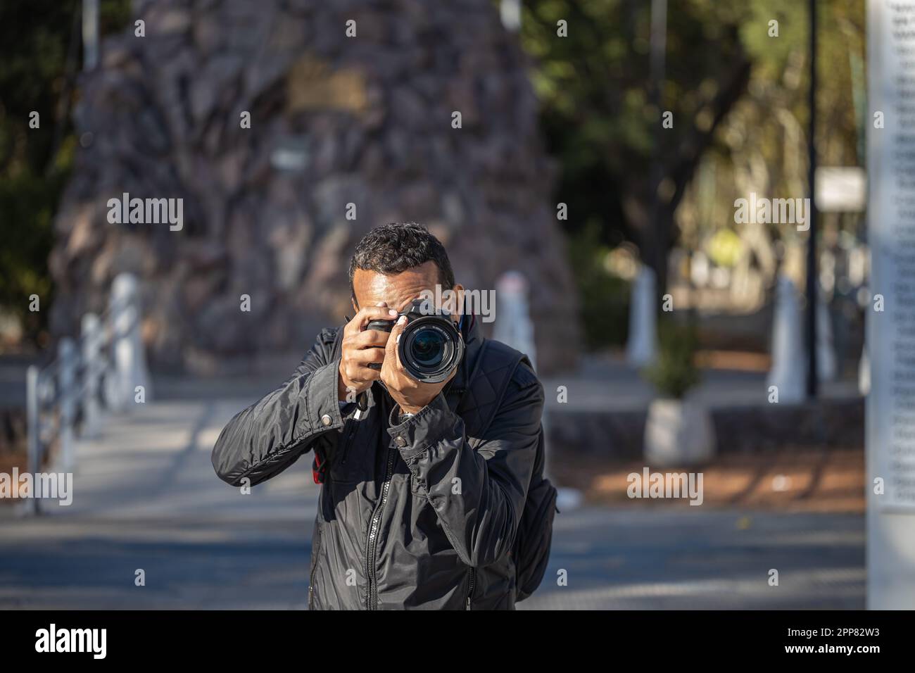 Ein lateinamerikanischer Fotojournalist, der ein Foto mit seiner Kamera macht. Stockfoto