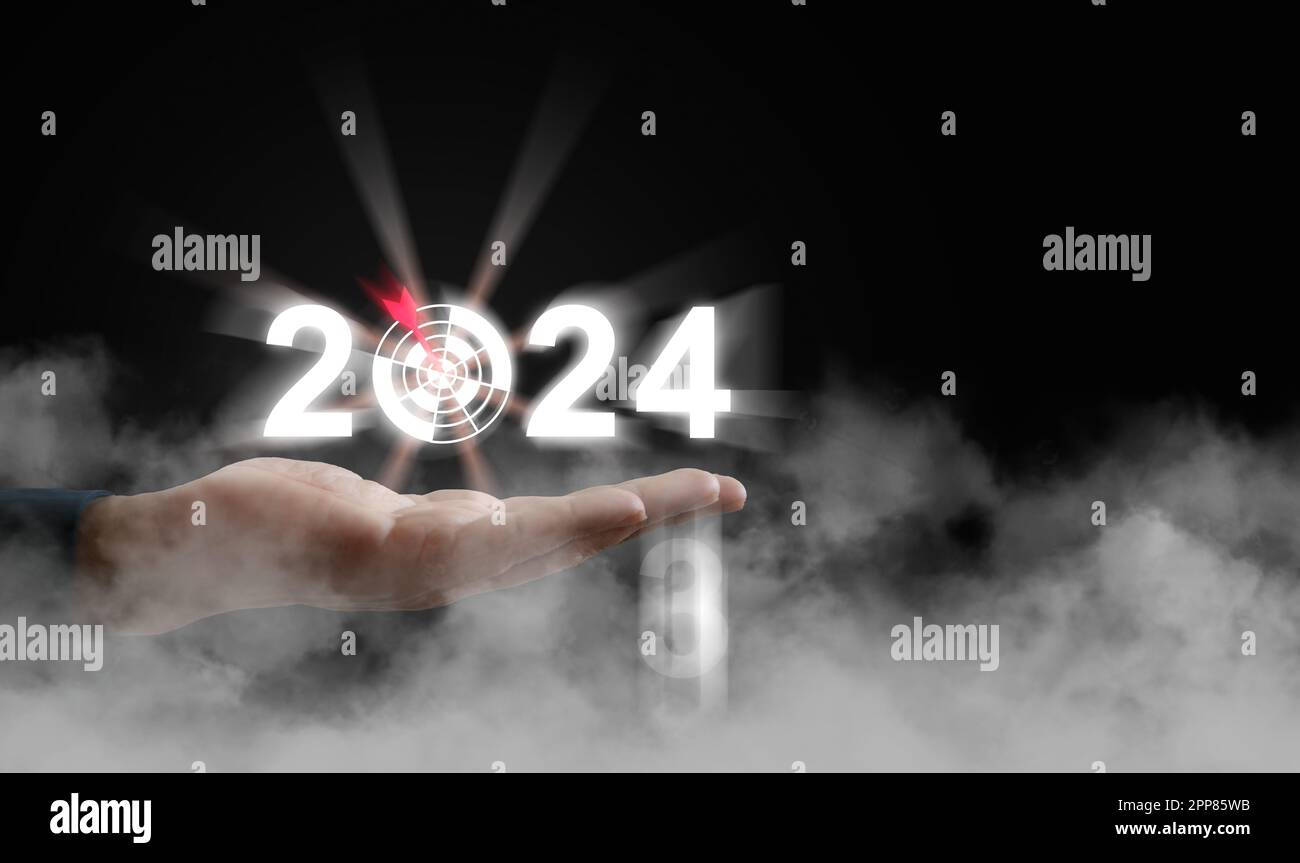 Eine Hand, die das Jahr 2024 mit einem Pfeil hält, und ein Ziel über der Wolke. Beginn des neuen Jahres, Geschäft, Projekt, Pfad, Ziel, Oder das Leben. Kontrollieren, verwalten, wählen Stockfoto