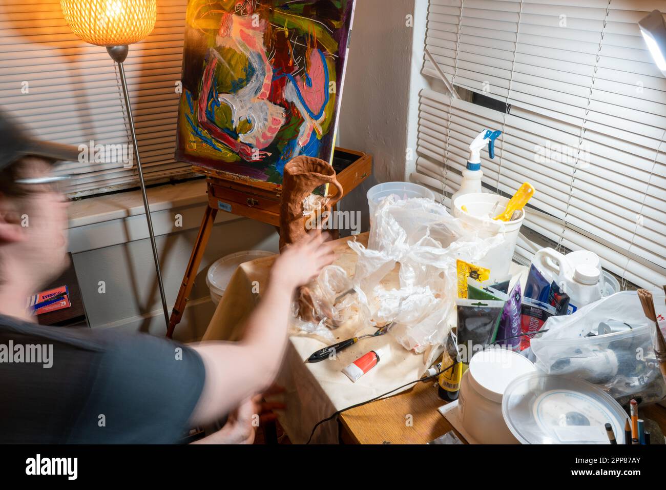 Denver, Colorado, USA - 4.21.2023: Künstler, der an einem Gemälde und einer Tonskulptur arbeitet Stockfoto