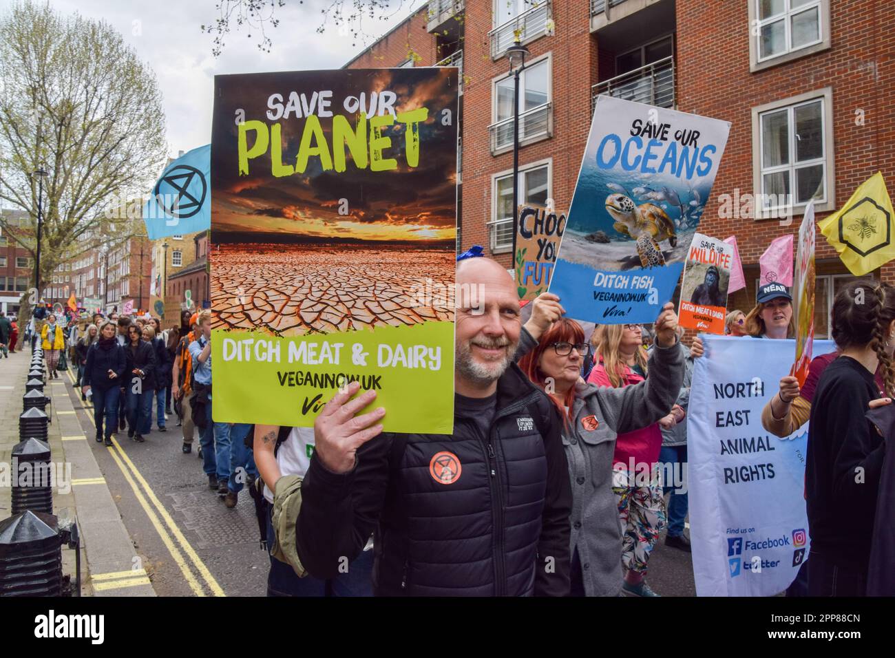 London, Großbritannien. 22. April 2023. Ein Protestteilnehmer hält während der Demonstration ein Plakat, auf dem die Menschen aufgefordert werden, vegan zu werden, um den Planeten zu retten. Tausende von Menschen marschierten durch Westminster, um gegen die Zerstörung der Natur, den Verlust der biologischen Vielfalt und den Klimawandel am Tag der Erde zu protestieren. Kredit: SOPA Images Limited/Alamy Live News Stockfoto