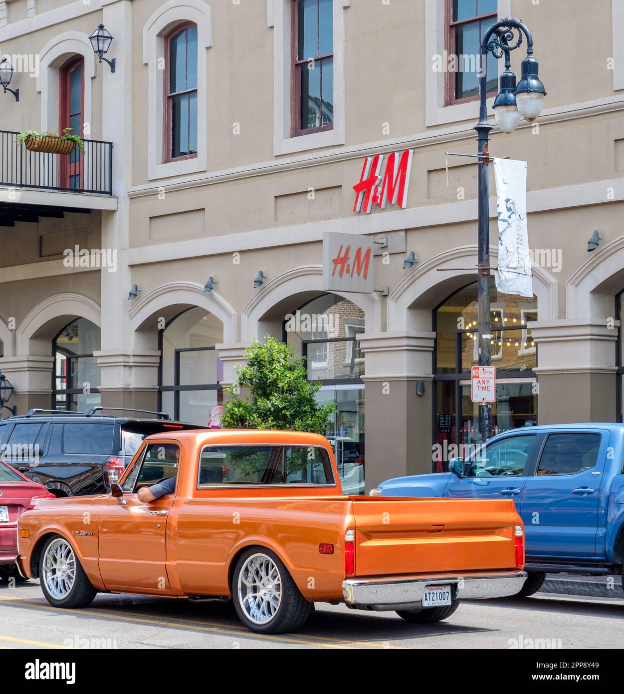 NEW ORLEANS, LA, USA - 2. APRIL 2023: Vor dem French Quarter H&M Store mit klassischem Pick-up im Verkehr Stockfoto