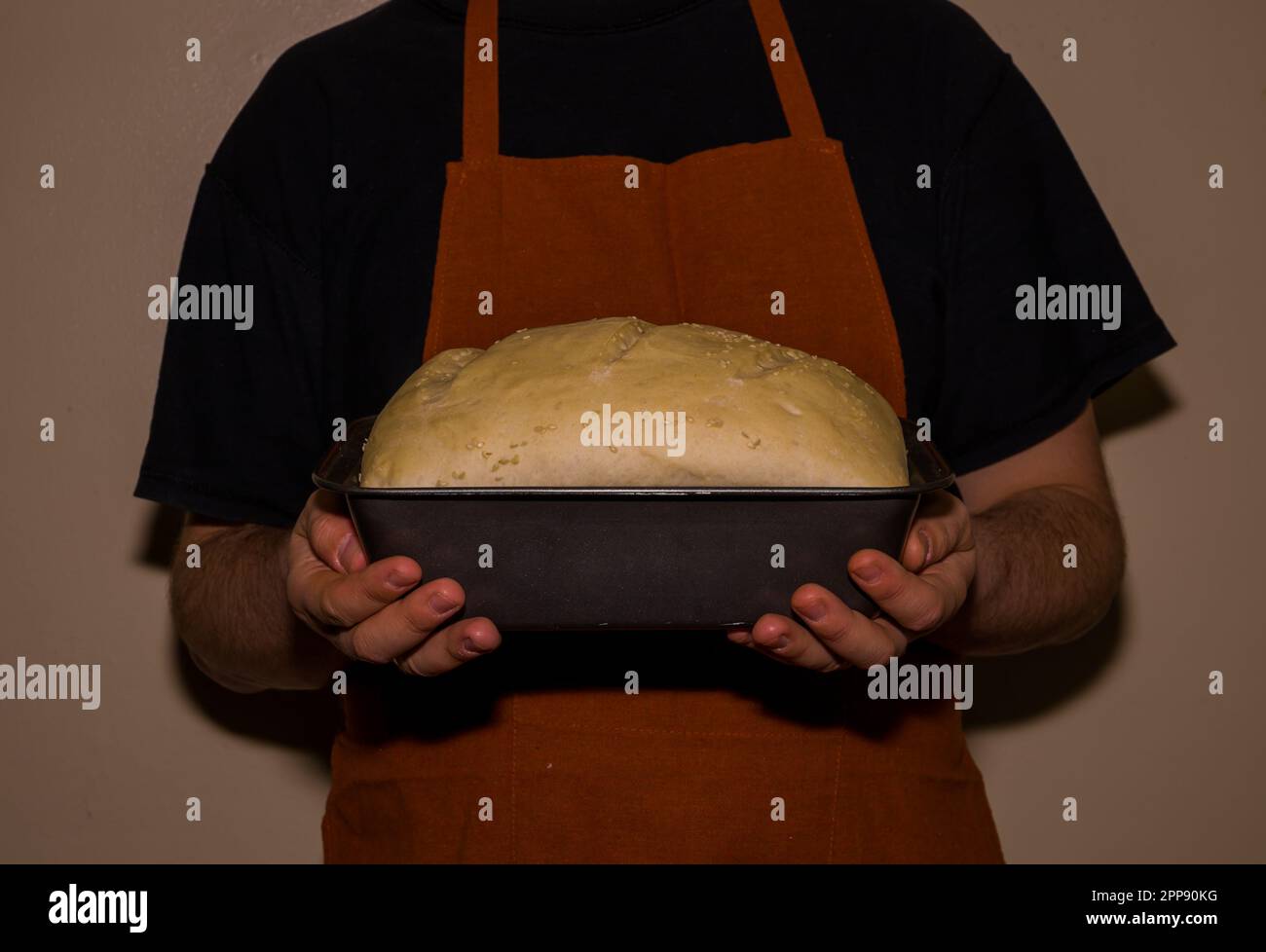 Baker in Schürze mit einem selbstgemachten Brotteig. Eine altmodische Bäckerei. Weltküche - Brot und Backwaren Stockfoto