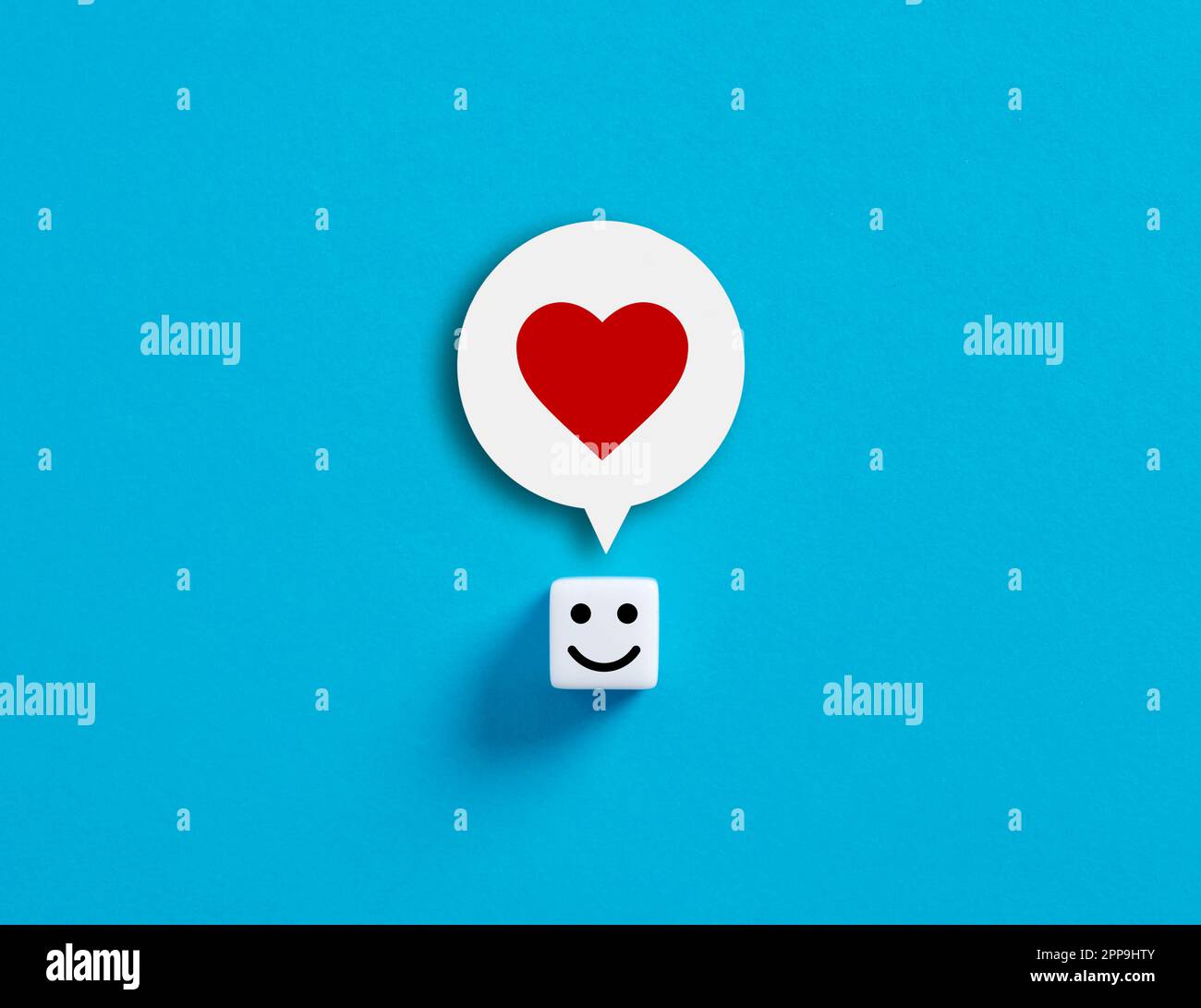 Liebe, Glück oder Social-Media-ähnliche Konzepte. Würfel mit fröhlichem Gesicht und Herzsymbol im Kopf. Stockfoto