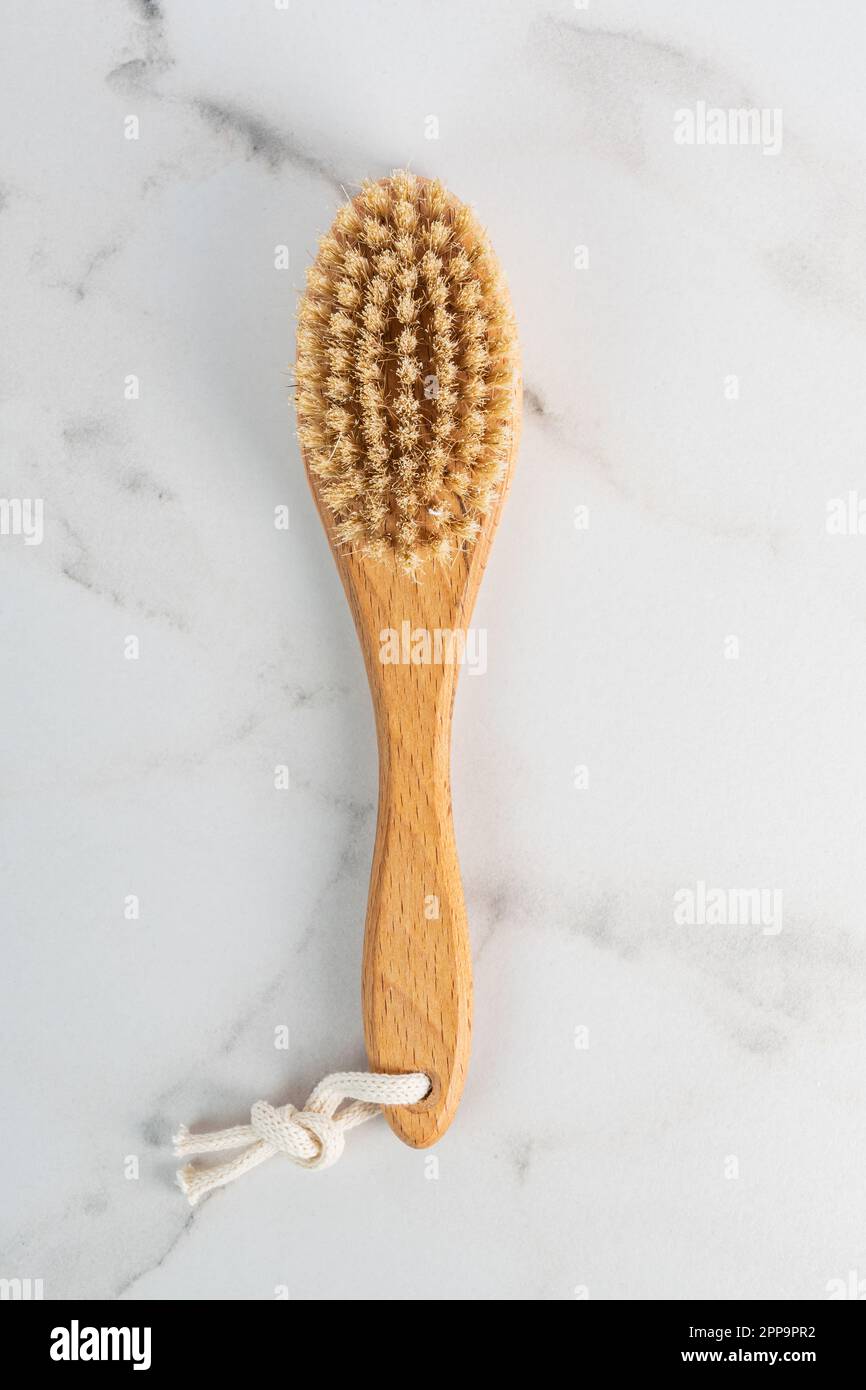 Holzbürste für trockene Körpermassage. Anti-Cellulitis-Bürste für Körper- und Fußmassage. Pinsel für Draufsicht auf Marmorhintergrund Stockfoto