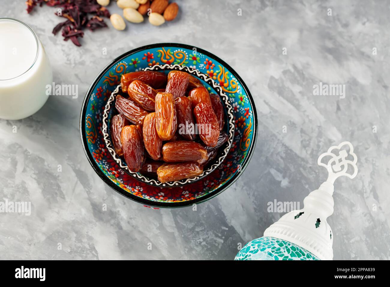 Getrocknete Datteln und Nüsse auf grauem Hintergrund. Traditionelles iftar Food und türkische Lampe auf Beton. Ramadan-Konzept. Draufsicht Stockfoto