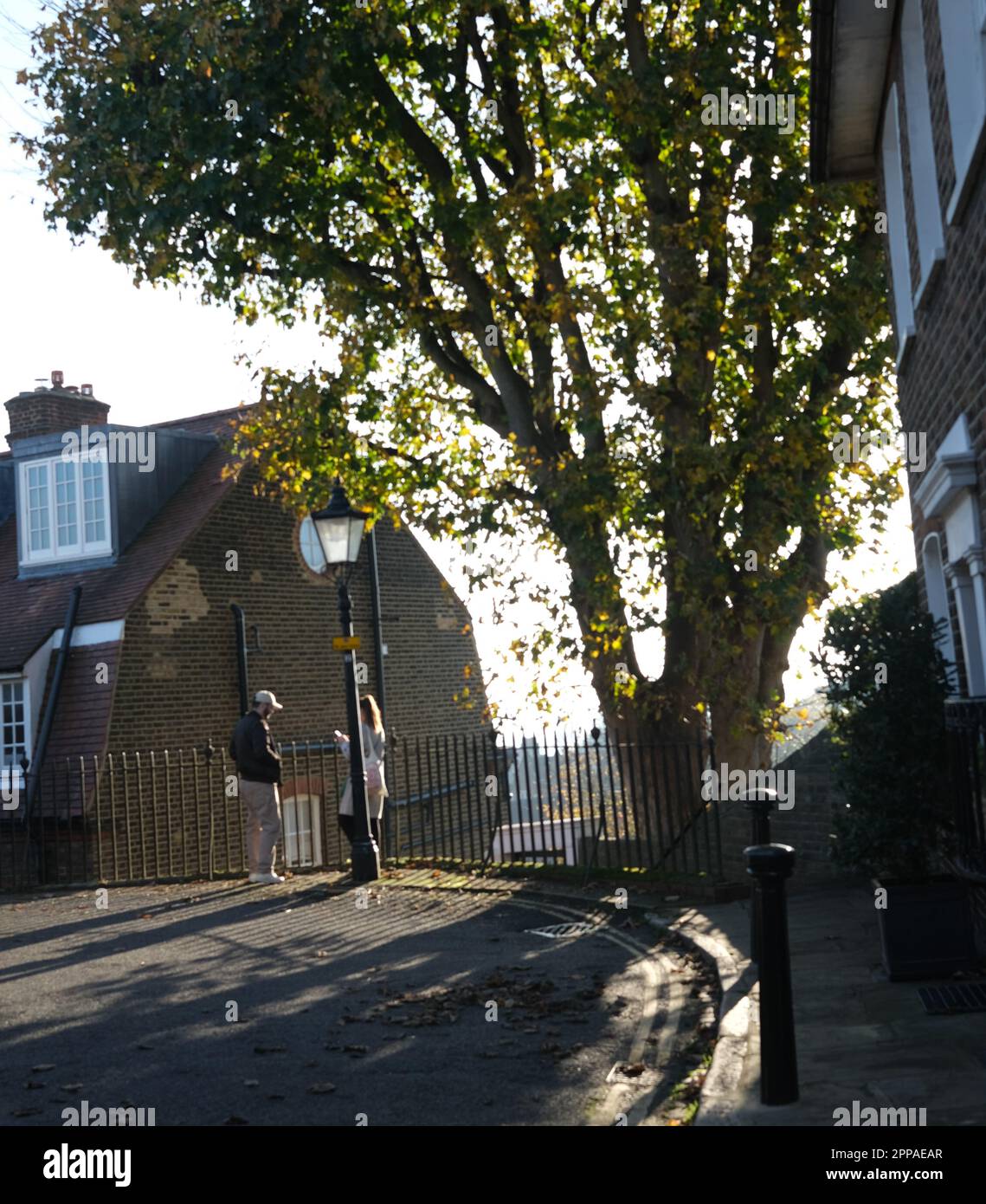 Ein Schaft von frühabendlichem Sonnenlicht leuchtet auf einen Mann und eine Frau, die im Februar 2023 in einer gemütlichen Ecke von Hampstead, Nord-London, miteinander in Kontakt treten Stockfoto