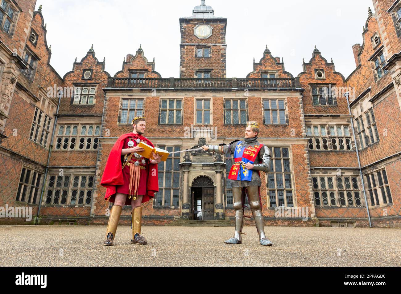 Birmingham, Großbritannien. 23. April 2023. Die Schauspieler Alexander Beard und Ralph Oakley, die als Julius Caesar und Henry V verkleidet sind, posieren mit einer moderneren Auflage von Shakespeares Stücken in der Aston Hall, Birmingham. Anlässlich des Geburtstags von Shakespeare am 23. April stellt Aston Hall, Teil des Birmingham Museum's Trust, das seltene erste Folio aus dem Jahr 1623 aus. Birminghams erstes Folio ist einzigartig, da es sich im Besitz der Menschen der Stadt als Teil der Bibliothek befindet. Kredit: Peter Lopeman/Alamy Live News Stockfoto