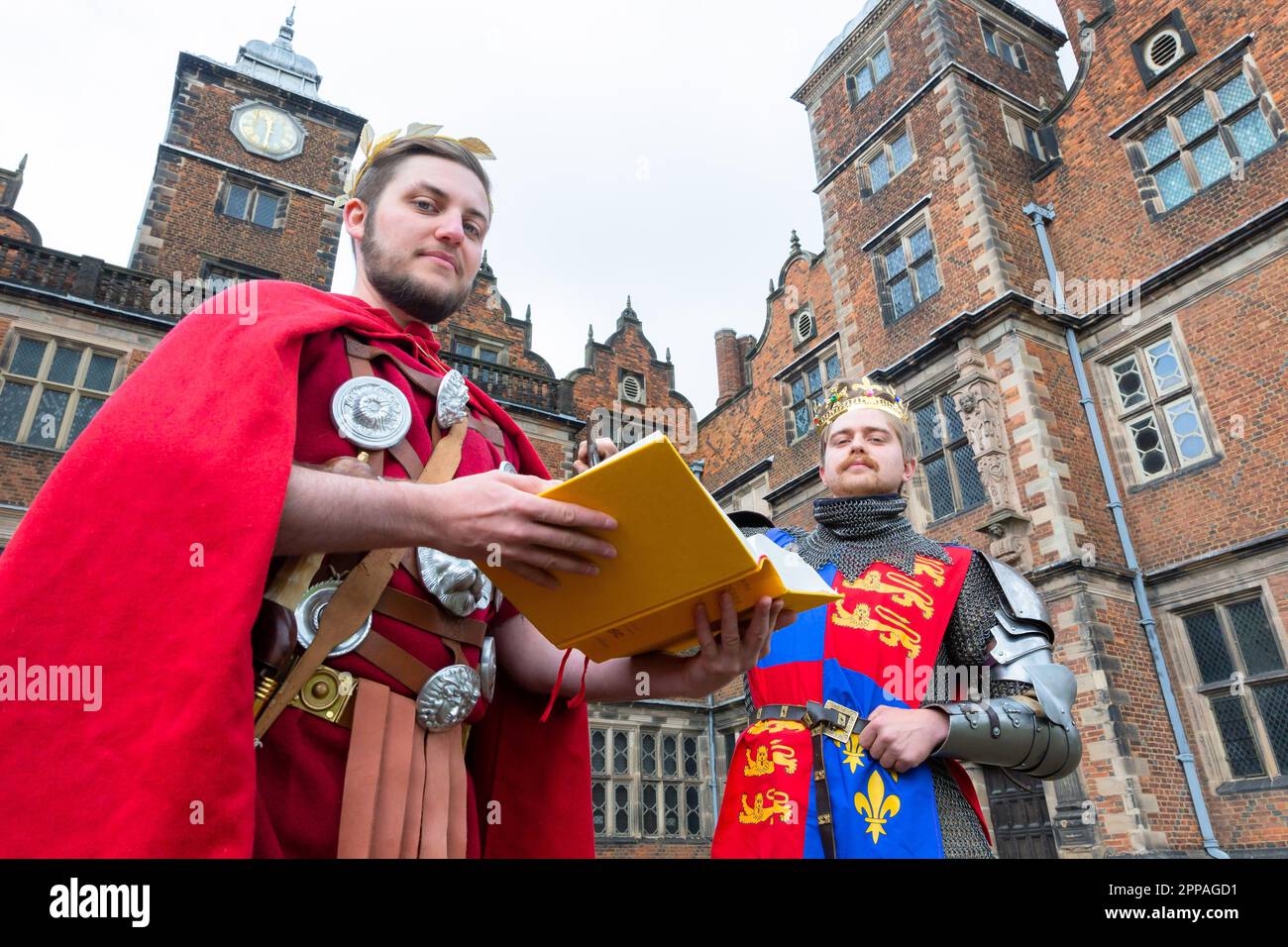 Birmingham, Großbritannien. 23. April 2023. Die Schauspieler Alexander Beard und Ralph Oakley, die als Julius Caesar und Henry V verkleidet sind, posieren mit einer moderneren Auflage von Shakespeares Stücken in der Aston Hall, Birmingham. Anlässlich des Geburtstags von Shakespeare am 23. April stellt Aston Hall, Teil des Birmingham Museum's Trust, das seltene erste Folio aus dem Jahr 1623 aus. Birminghams erstes Folio ist einzigartig, da es sich im Besitz der Menschen der Stadt als Teil der Bibliothek befindet. Kredit: Peter Lopeman/Alamy Live News Stockfoto
