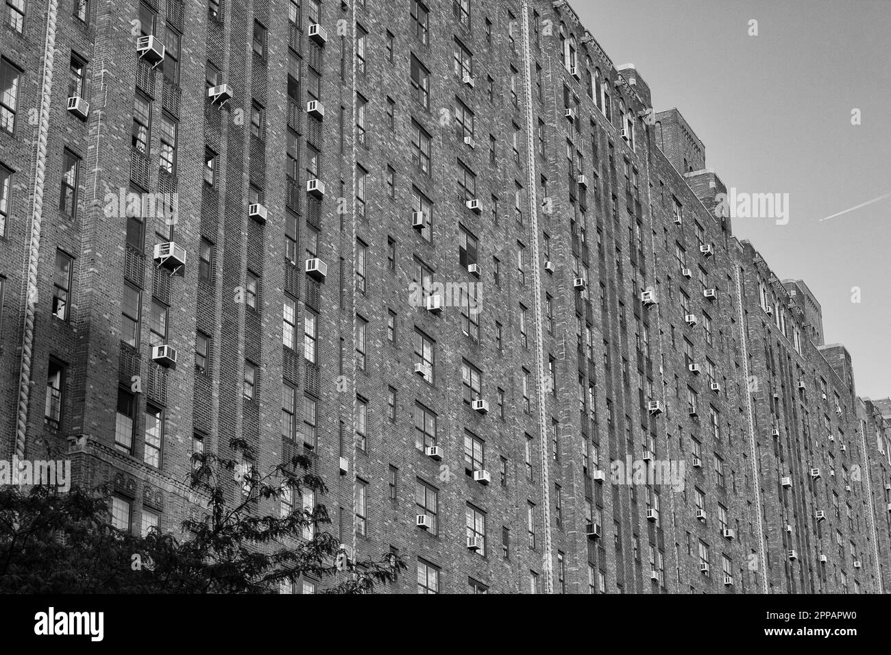 Wohnbauwand mit Fenstern und Klimaanlagen in New York City in Schwarz und Weiß Stockfoto