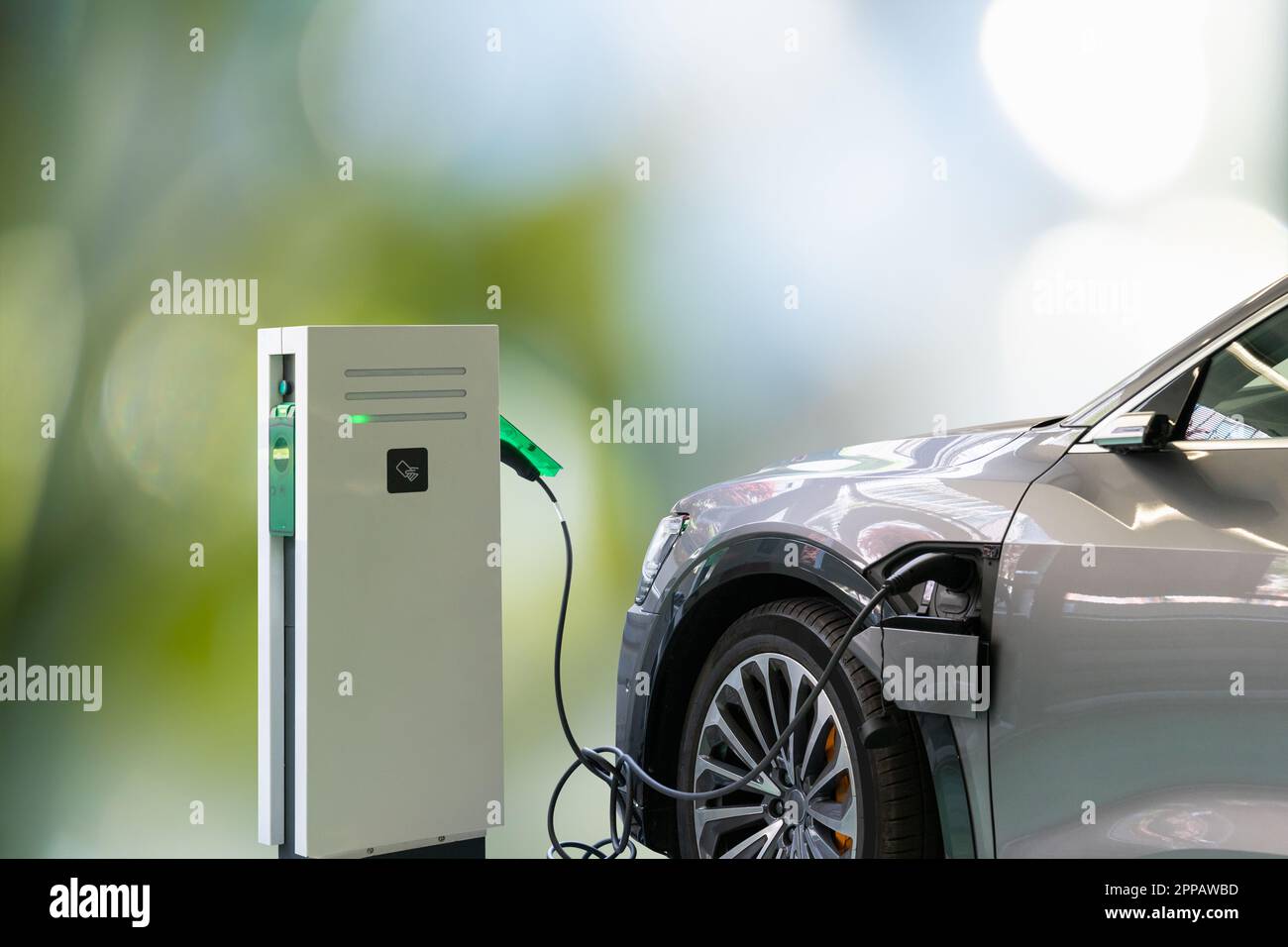 Elektroauto mit angeschlossenem Ladekabel auf grünem Hintergrund. Hochwertiges Foto Stockfoto