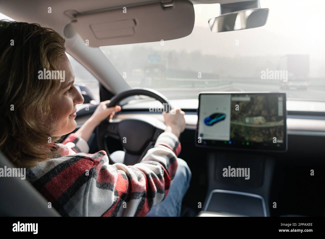 Frau, die ein Elektroauto auf einer Autobahn fährt. Hochwertiges Foto Stockfoto