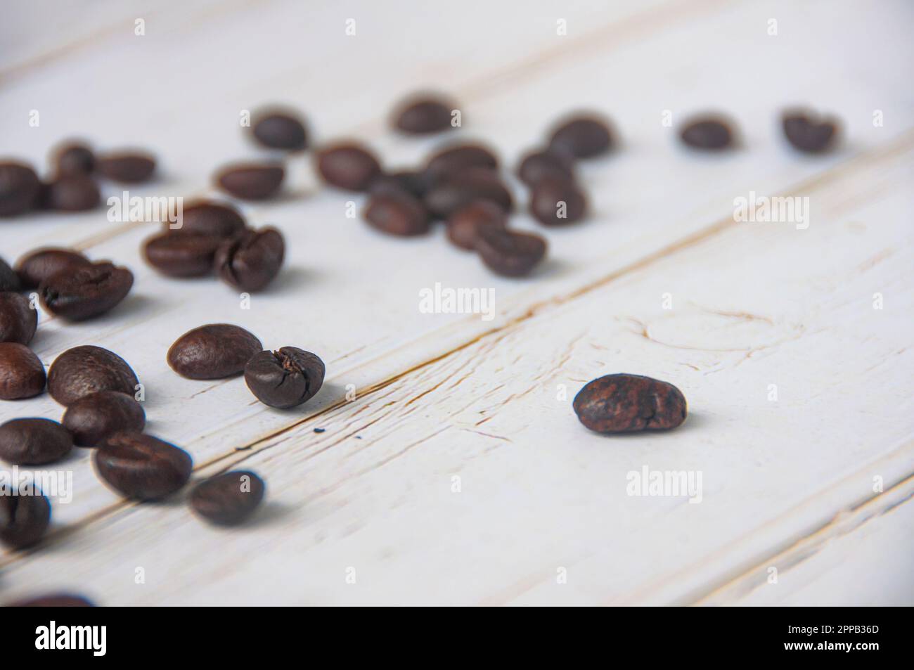Verstreute Kaffeebohnen auf Holzbelag mit anpassbarem Platz für Text oder Kaffeeideen Stockfoto
