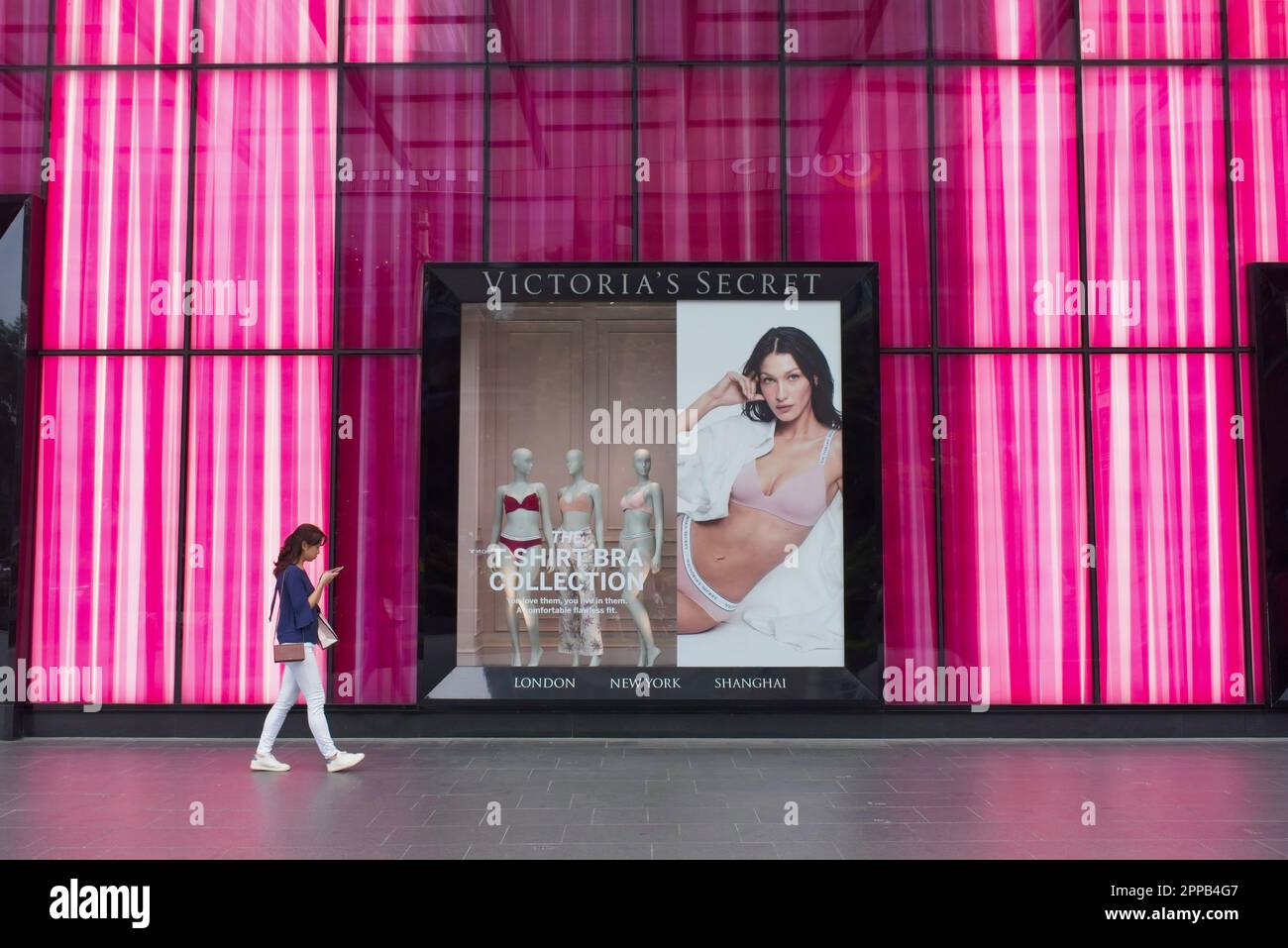 Eine junge Singapur-Frau kommt an einem pinkfarbenen Outlet Victoria's Secret in der Orchard Road, Singapur, vorbei, der berühmten Einkaufsstraße des Bundesstaates Stockfoto