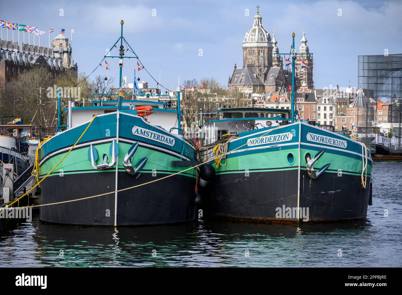Zwei Kanalboote mit ähnlichen Farbschemen im Oosterdok, Amsterdam Stockfoto