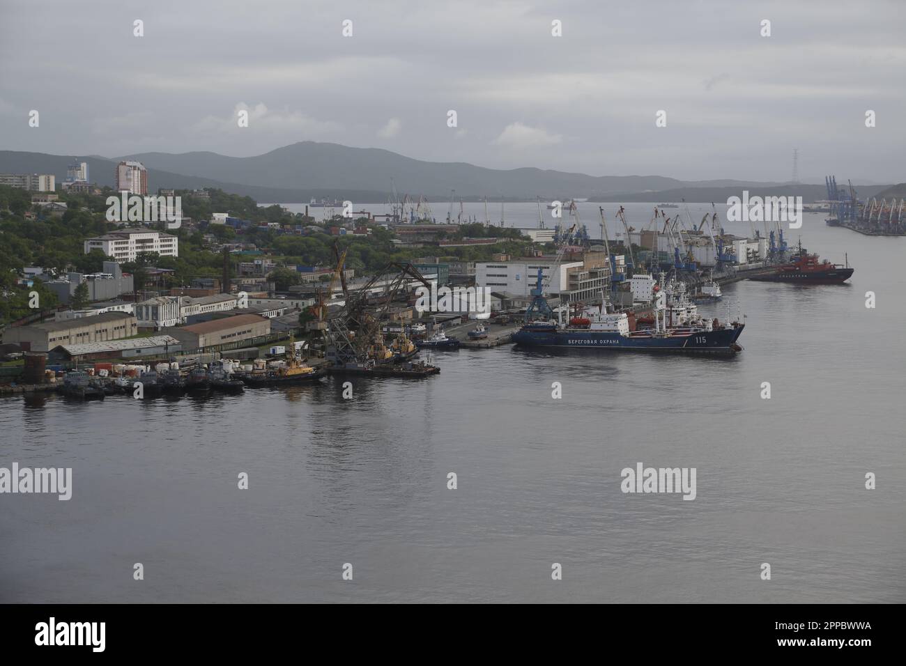 Blick auf den Hafen von Wladiwostok, Russland, mit Schiff der russischen Küstenwache, einem Bergungsschiff und vielen Hafenkranen Stockfoto