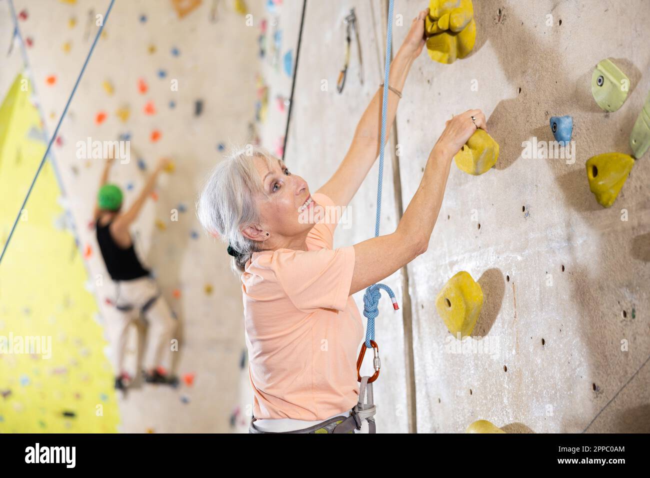 Eine entschlossene alte Dame, die im Kletterstudio schwer klettern kann Stockfoto