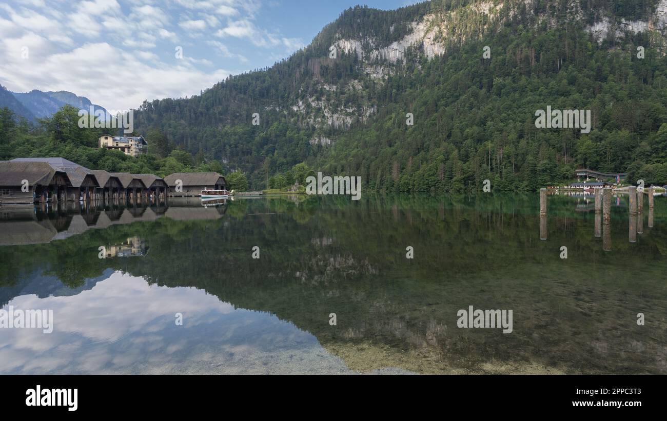 Am Ufer des stillliegenden alpinen Sees mit Hütten und Bootshäusern, Königssee, Deutschland Stockfoto