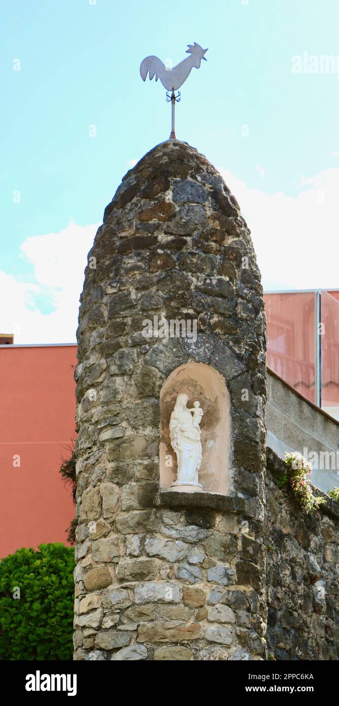 Madonna und Kind in einer Nische, die in eine Steinsäule mit einer hahnenförmigen Flügelscheibe auf den Comillas Cantabria Spanien gesetzt wurde Stockfoto