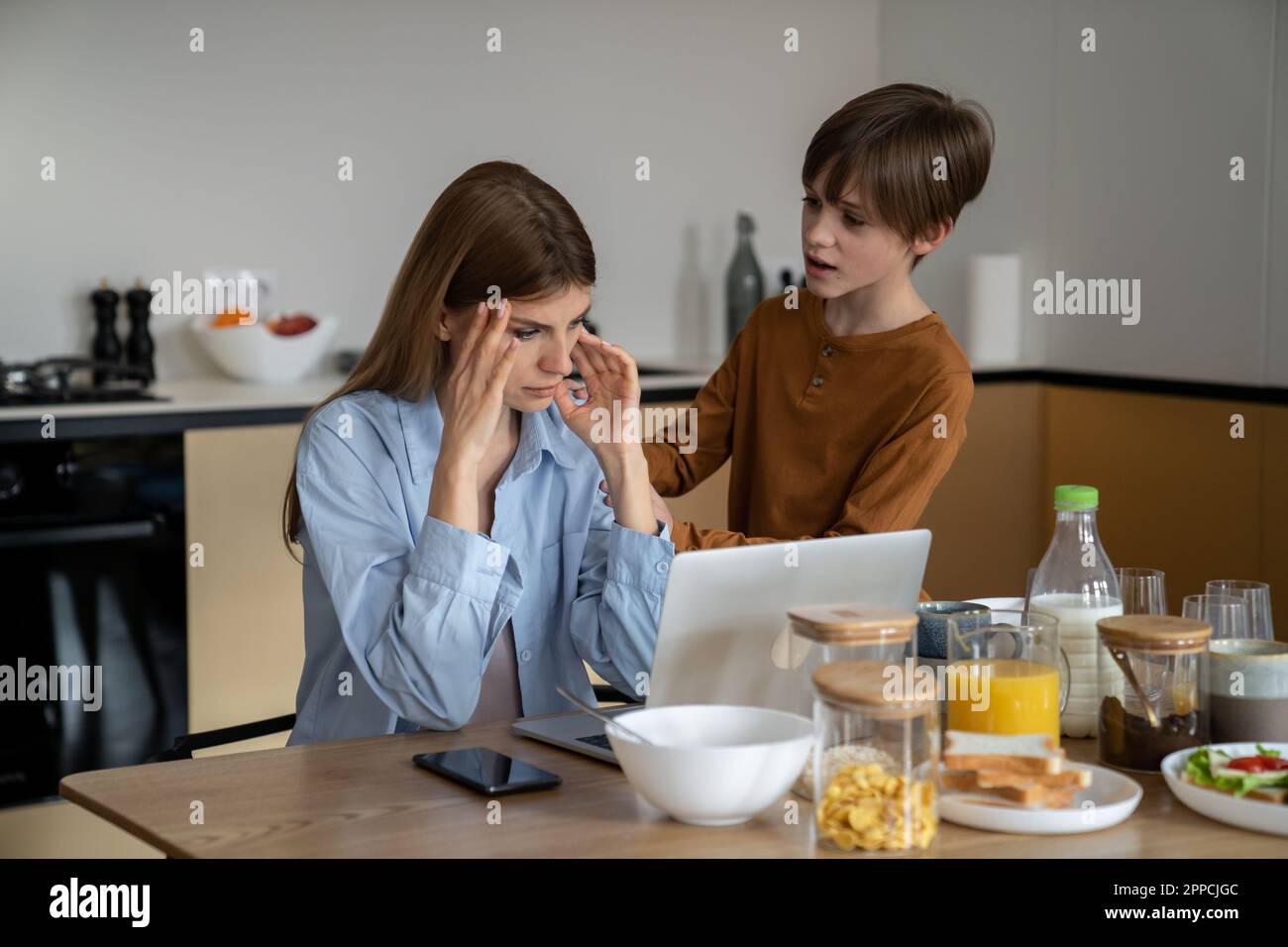 Freiberufliche Mutter, die mit einem Kind von zu Hause aus arbeiten will, schaut auf den Laptop-Bildschirm und versucht, sich zu konzentrieren Stockfoto