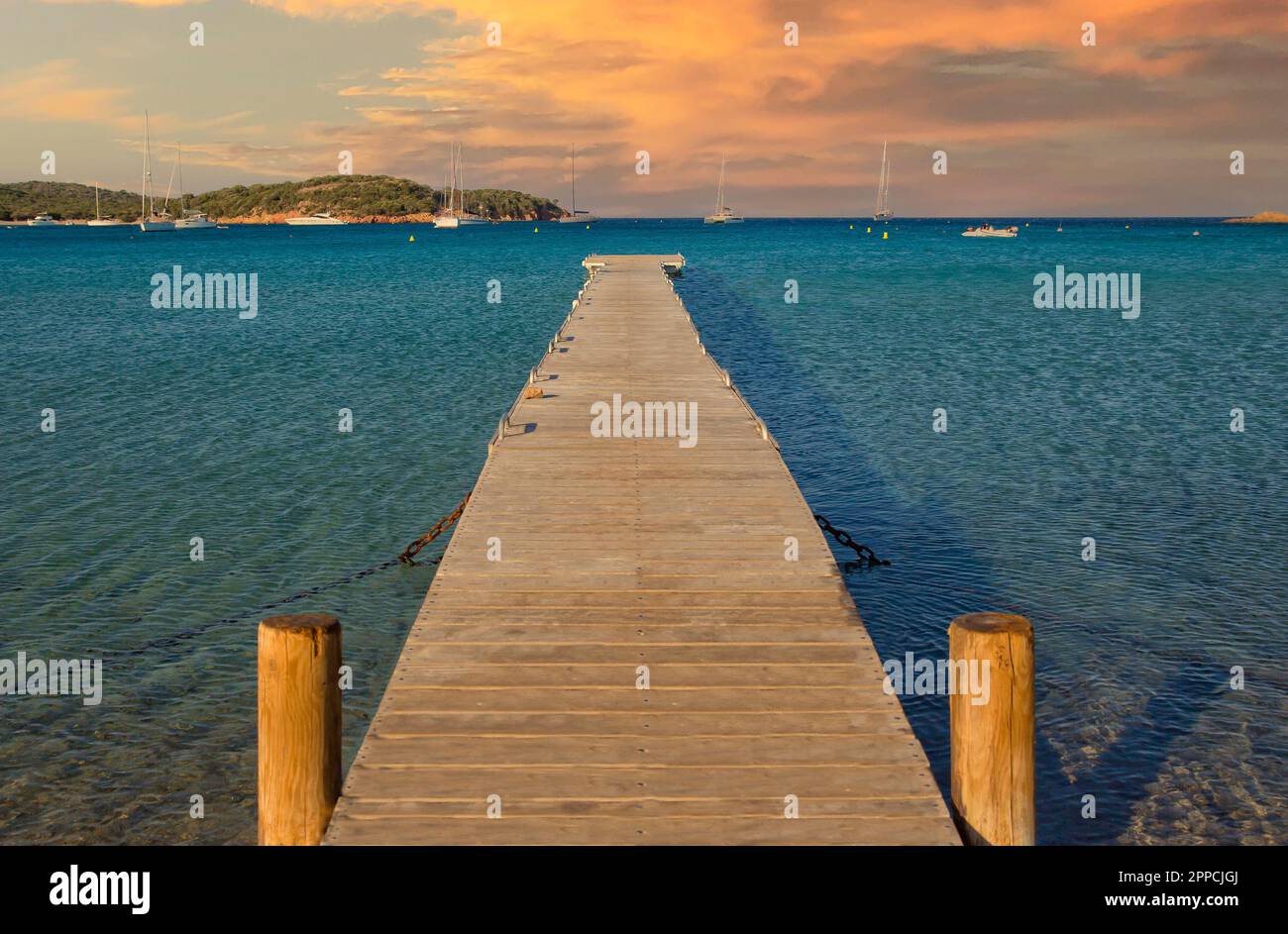 Malerischer Blick auf das blaue Meer und eine lange hölzerne Anlegestelle bei Sonnenuntergang am Strand von Rondinara, Insel Korsika, Frankreich Stockfoto