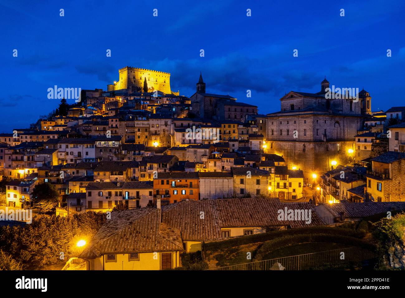 Beleuchtetes Castello Orsini über Häusern unter blauem Himmel bei Nacht Stockfoto
