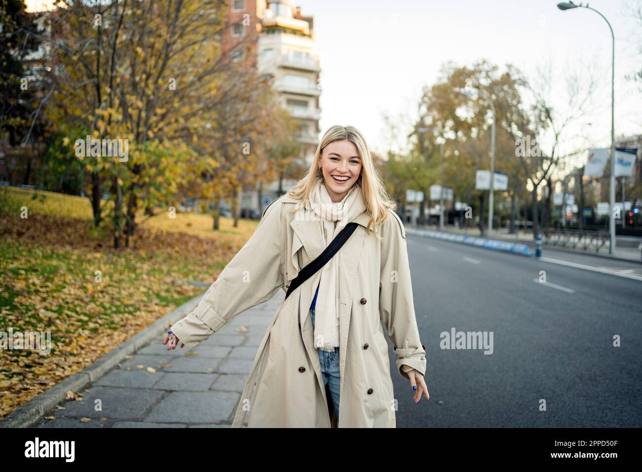 Glückliche Frau, die auf dem Bürgersteig in der Stadt spaziert Stockfoto