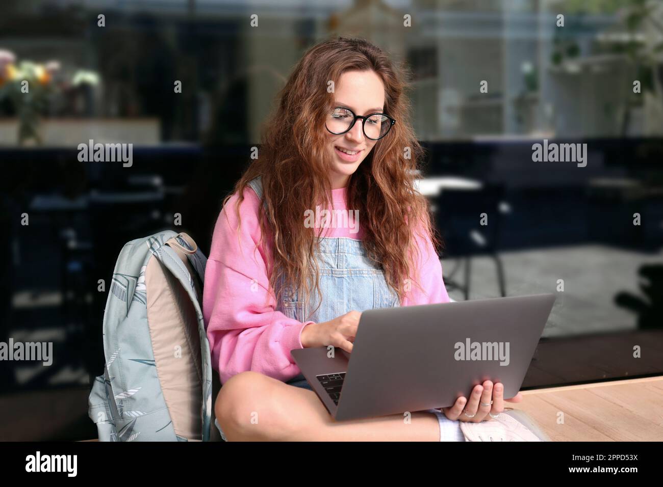 Lächelnder Student, der auf einem Laptop auf einer Bank sitzt Stockfoto