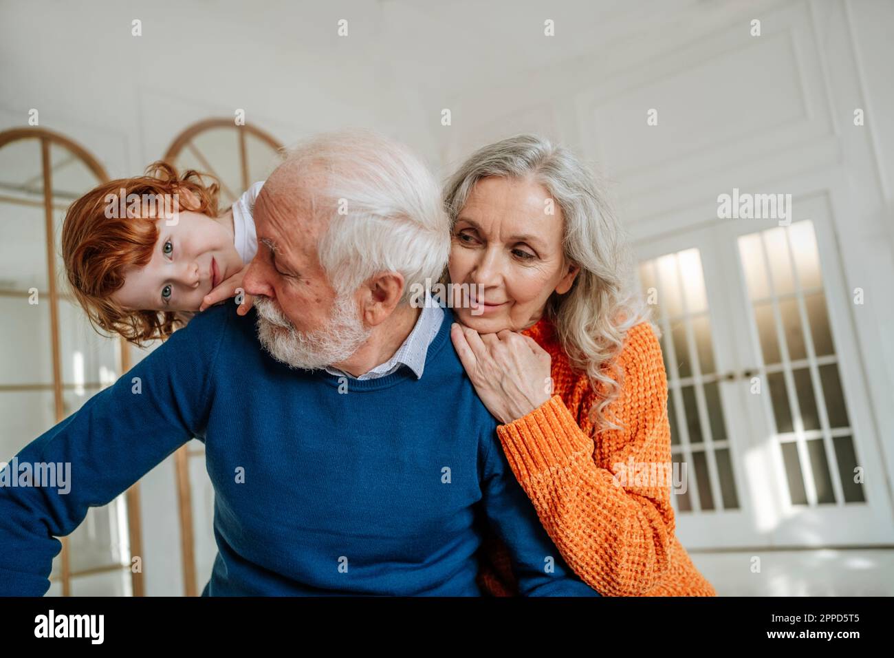 Verspielte Großeltern, die Spaß mit ihrem Enkel zu Hause haben Stockfoto