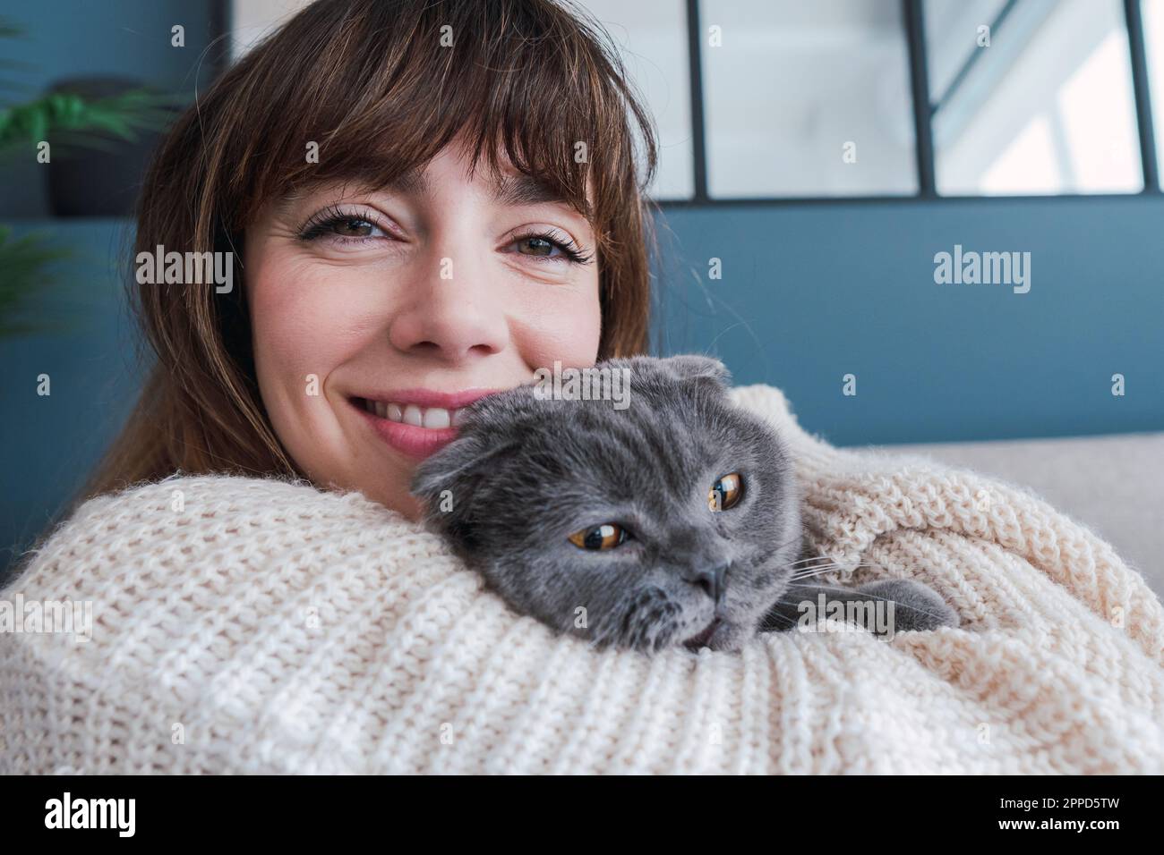 Lächelnde Frau umarmt Katze zu Hause Stockfoto