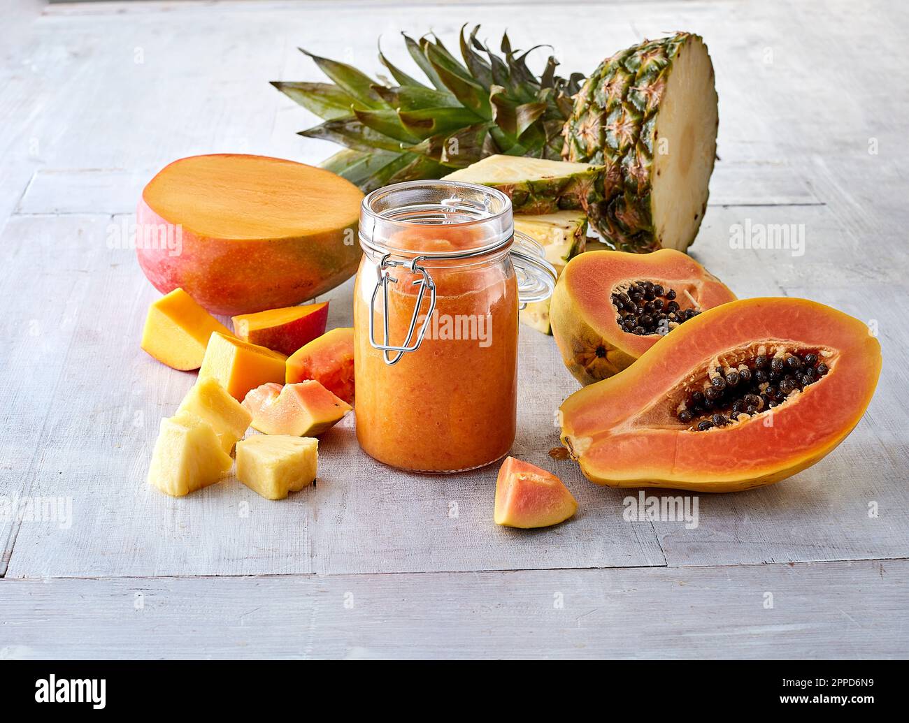 Halbierte Mangofrüchte, Papaya, Ananas und Smoothie im Glas Stockfoto
