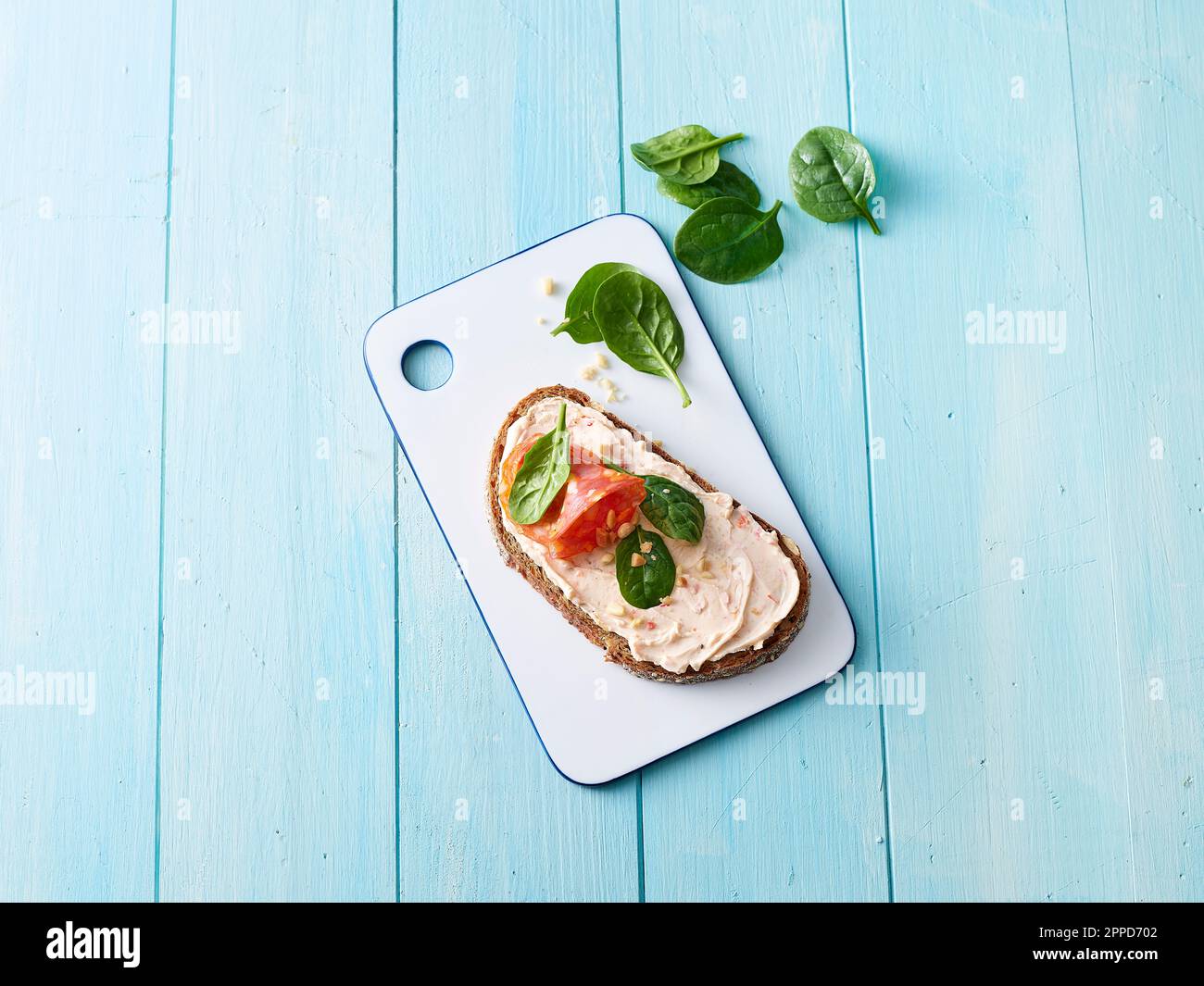 Studiofoto eines verzehrfertigen Sandwichs mit Frischkäse, Salami und Spinat Stockfoto