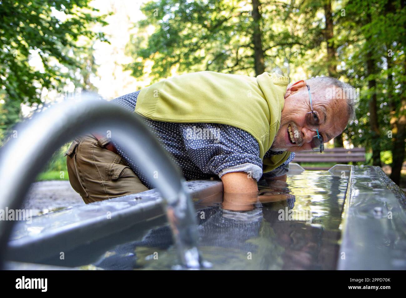 Glücklicher Senior-Mann, der sich in das Kneipp-Becken eintaucht Stockfoto