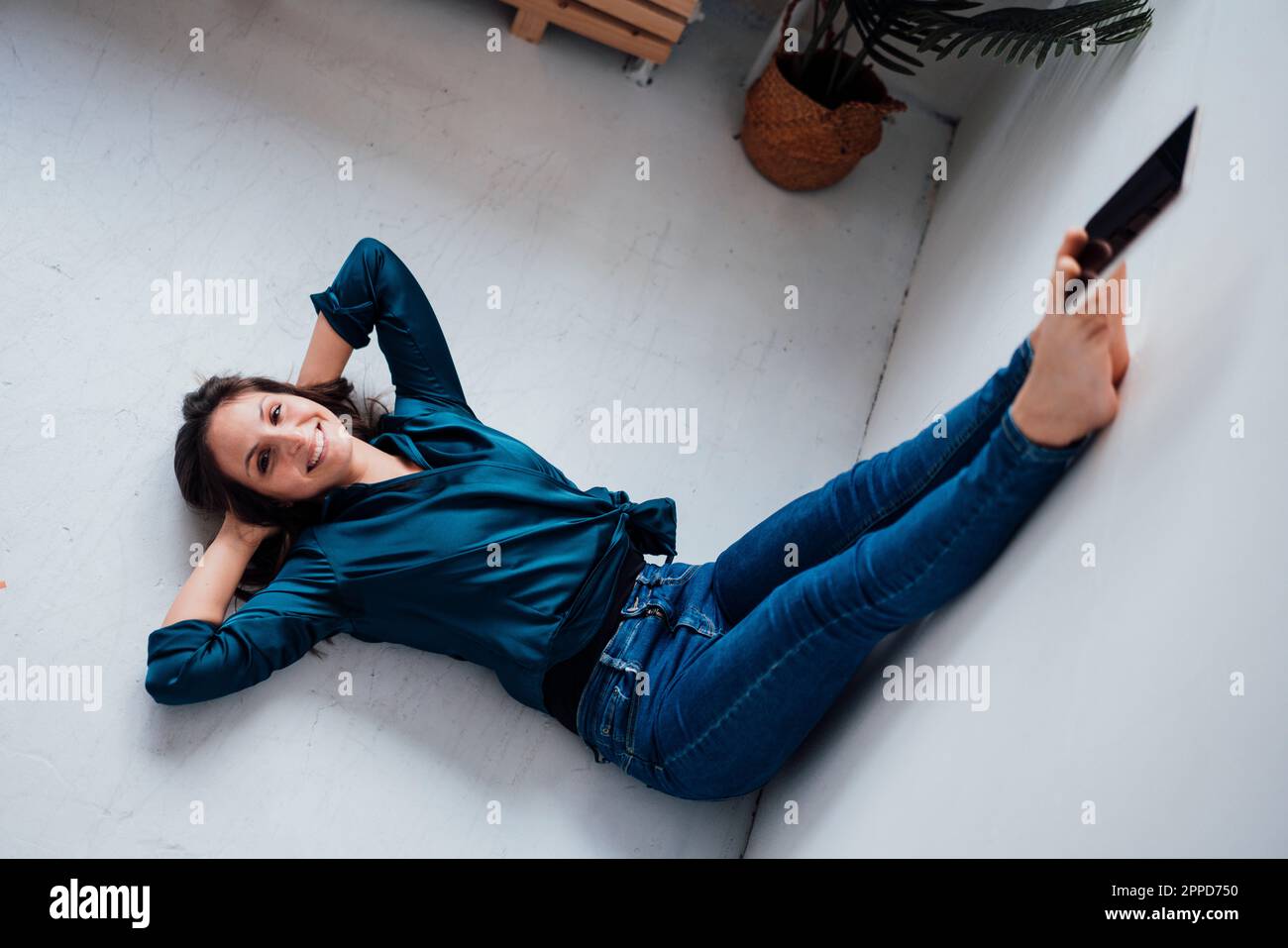 Junge Frau, die zu Hause einen Tablet-PC mit den Zehen in der Hand hält Stockfoto
