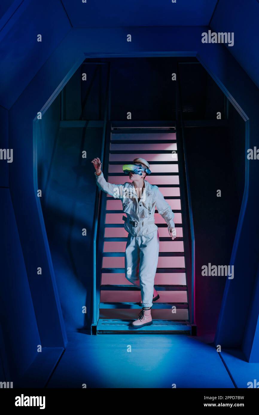 Junge Frau mit Virtual-Reality-Simulator, die auf Treppen runterkommt Stockfoto