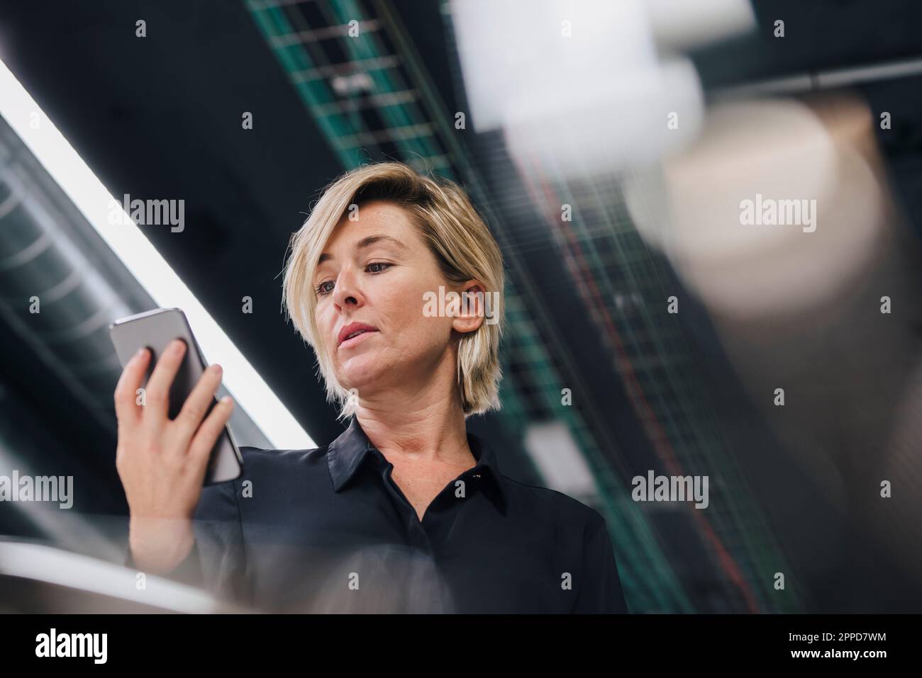 Geschäftsfrau, die im Büro auf ein Smartphone schaut Stockfoto