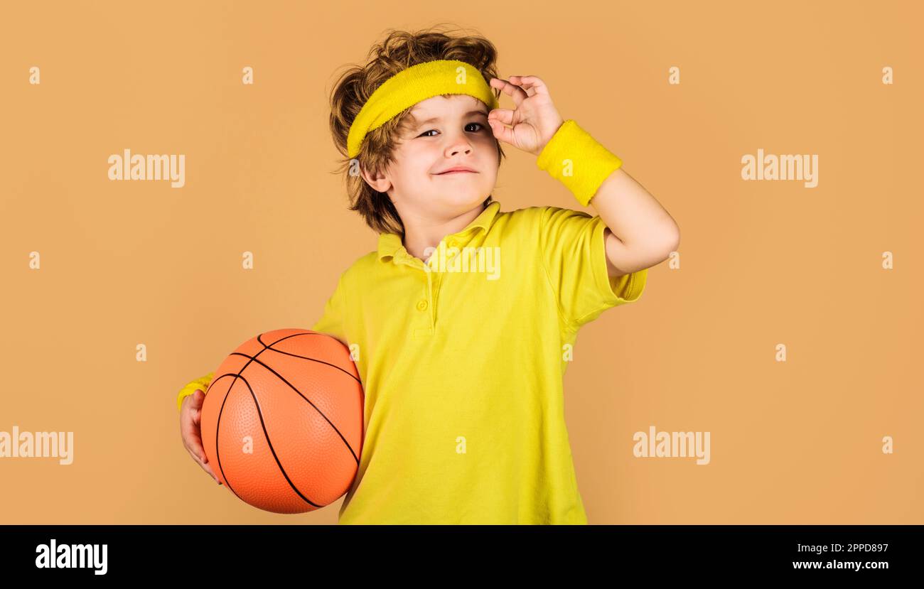 Lächelndes Kind mit Basketballball, das das Zeichen „OK“, „ausgezeichnetes Symbol“ zeigt. Basketballspiel. Aktivitäten für Kinder. Kleiner Basketballer. Sportausrüstung. Kindheit Stockfoto