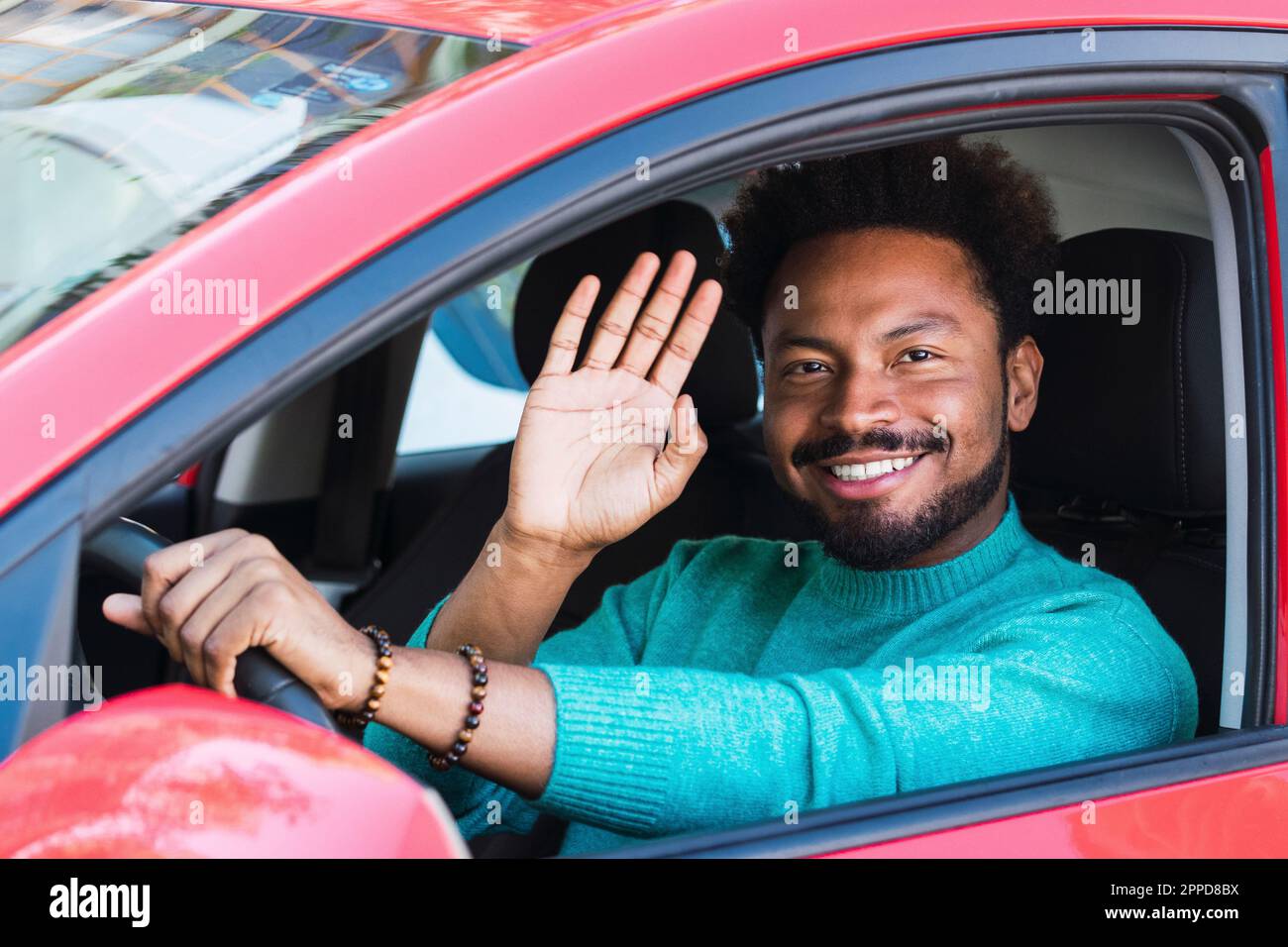 Ein lächelnder Mann, der im Auto winkt Stockfoto