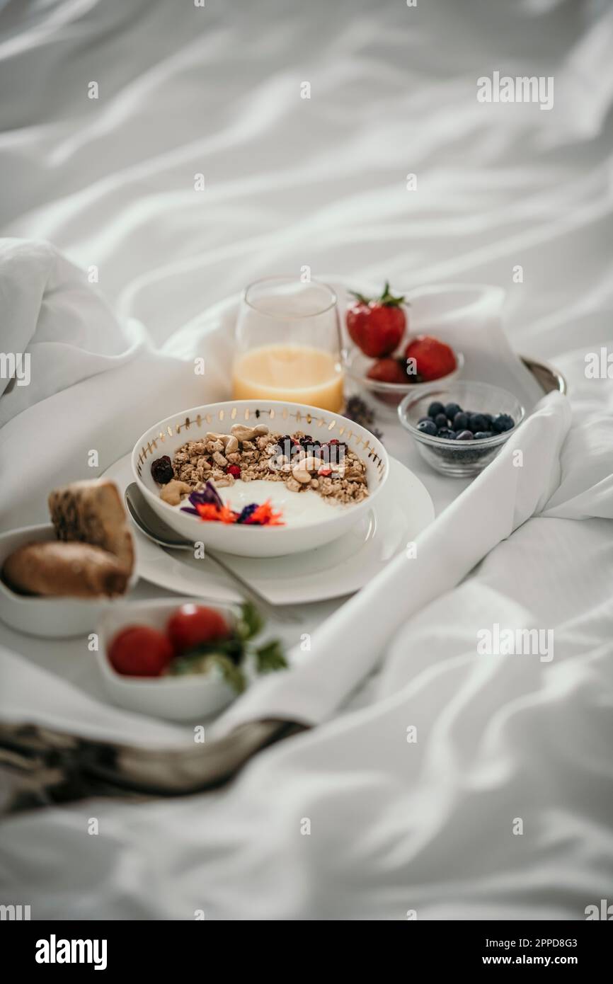 Tablett mit frischem Frühstück auf dem Bett Stockfoto