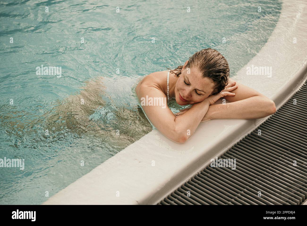 Frau mit geschlossenen Augen, die sich im Schwimmbad ruht Stockfoto