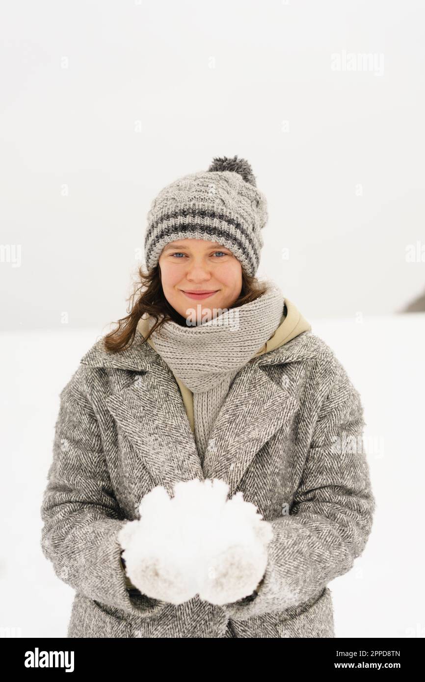 Lächelnde Frau mit Strickmütze und Schnee Stockfoto