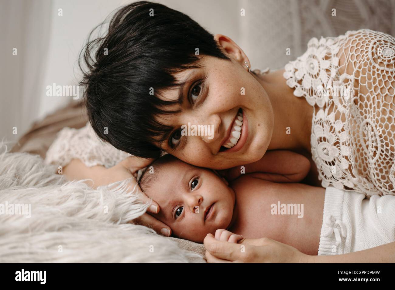Glückliche Mutter mit neugeborenem Baby, das auf dem Bett liegt Stockfoto
