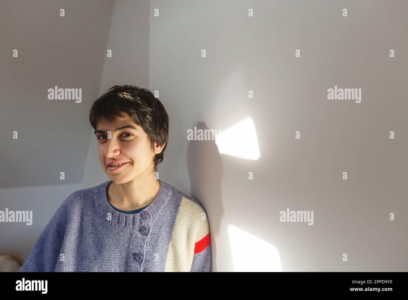 Lächelnde Frau mit kurzen Haaren, die an der Wand stand Stockfoto
