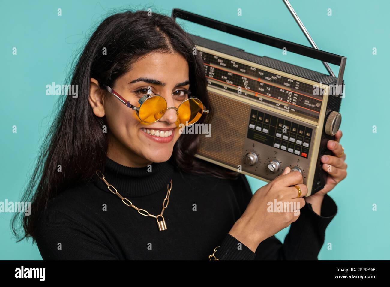 Eine indische Frau, die mit einem Retro-Plattenspieler Musik hört, Disco-Tänze oder Lieblingstitel tanzt, Spaß hat, Unterhaltung hat, Fan von Vintage-Technologien ist. Hübsches hindu-Mädchen isoliert auf blauem Hintergrund Stockfoto