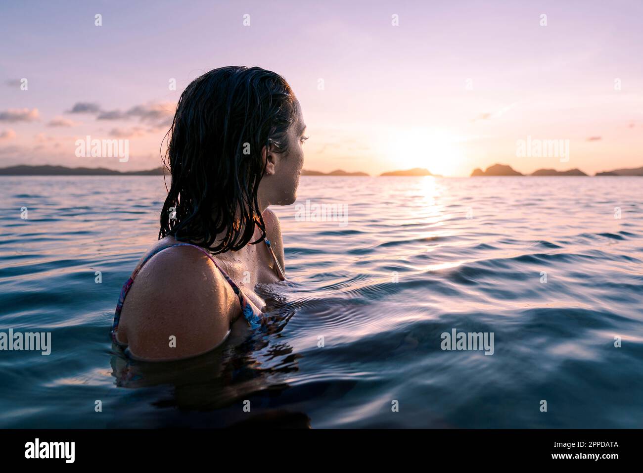 Eine Frau, die im Meer schwimmt und die Sonne ansieht Stockfoto