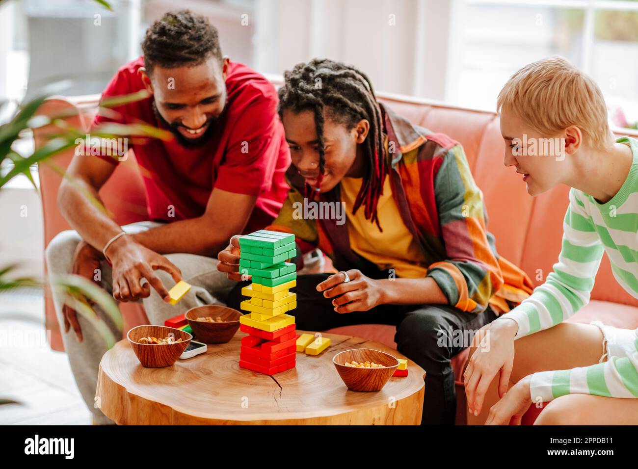 Fröhliche Multirassenfreunde, die zu Hause ein Spiel zum Entfernen von Blöcken spielen Stockfoto