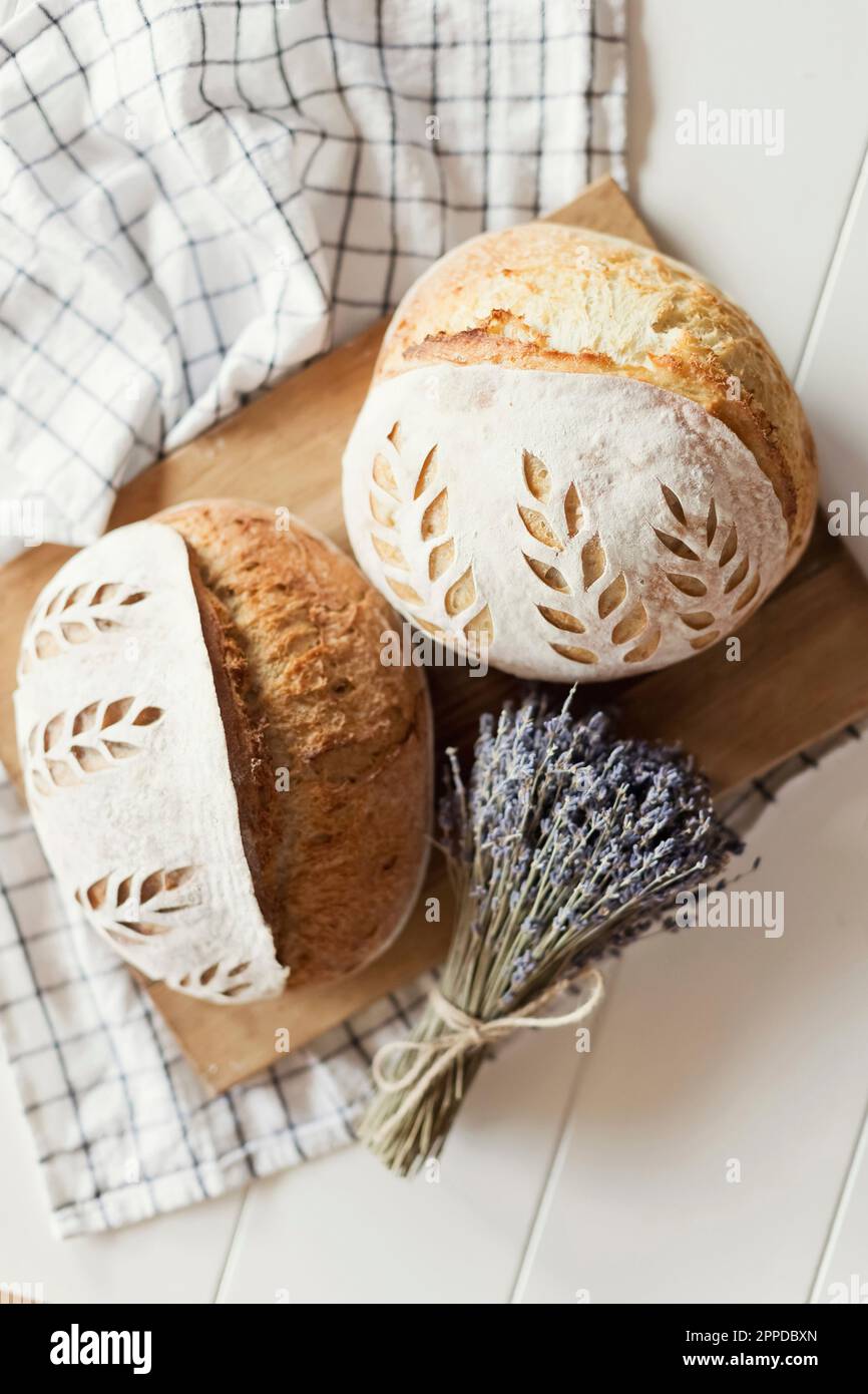 Frisch gebackenes Brot mit trockenen Lavendelblumen auf dem Tisch Stockfoto