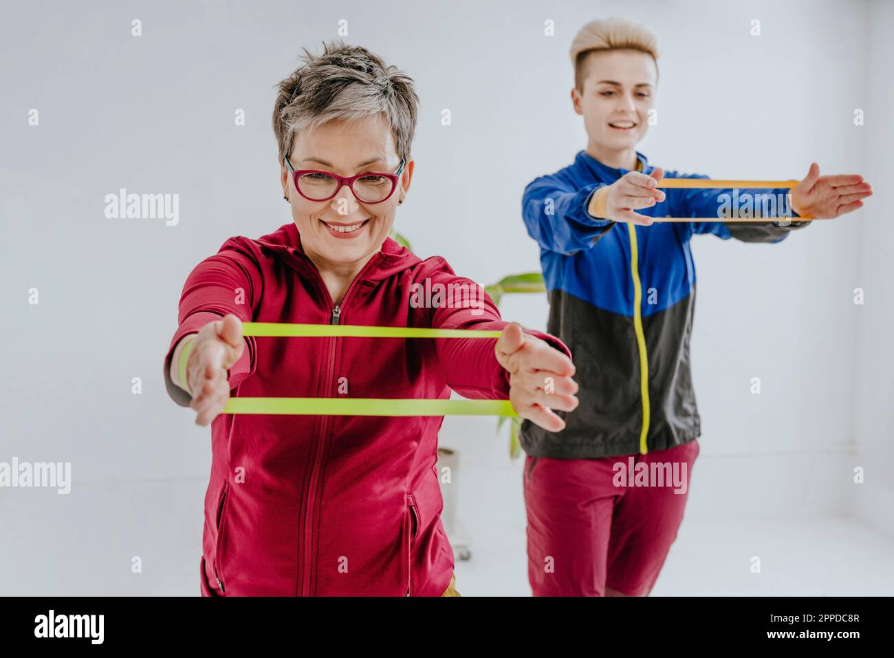Mutter und Tochter beim Training mit Widerstandsbändern vor der weißen Wand Stockfoto