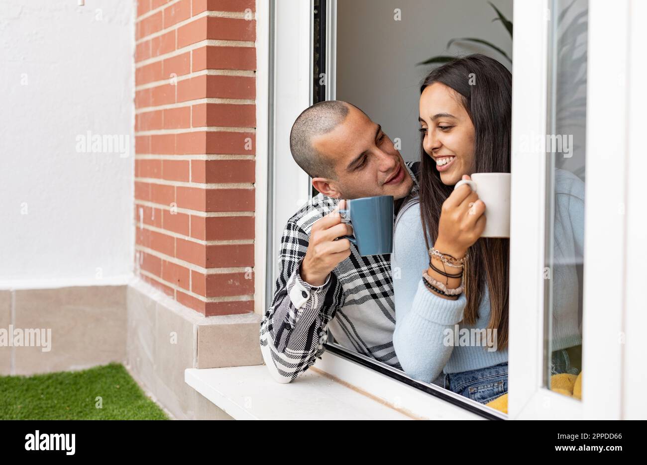 Glückliches Paar, das zu Hause Kaffee am Fenster trank Stockfoto
