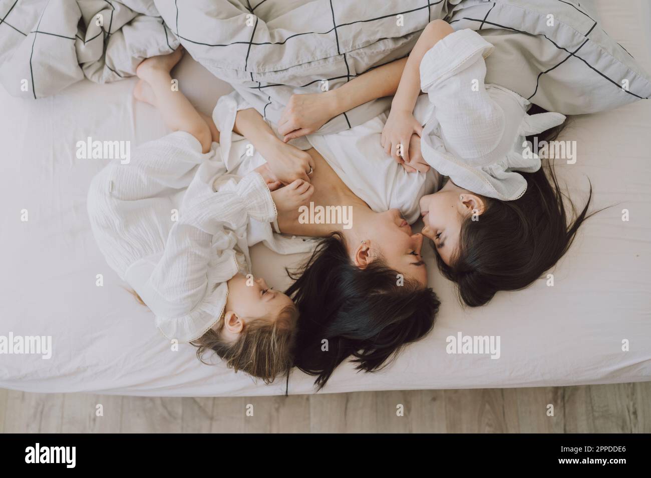 Glückliche Mutter und Töchter im Bett Stockfoto